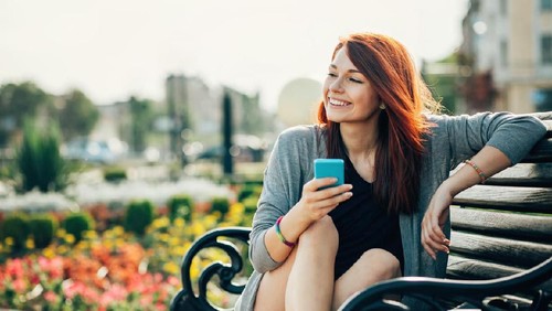 Joyful woman enjoying the freedom of the beach standing with open arms and a happy smile looking up towards the sky