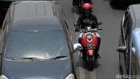 Diapit dua mobil, pemotor ini asyik main ponsel.
