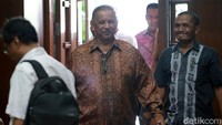 Sofyan Basir nampak mengenakan kemeja batik dan tersenyum saat memasuki ruang sidang.