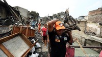 Warga sibuk mengangkut barang-barang seperti sepeda yang tinggal kerangkanya.