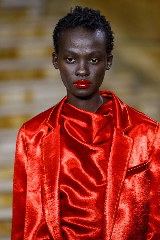 Makeup artist Nami Yoshida membuat tampilan makeup yang glowing untuk model Sies Marjan. Yoshida menggunakan pelembab pada wajah untuk membuat tampilan kulit terliat lebih mengkilap. Untuk menyempurnakannya, Yoshida menggunakan lip gloss berwarna merah. Foto: Getty Images