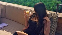 Sambil memegang minuman segar berwarna kuning, ia pose candid dan memperlihatkan pemandangan pantai di belakangnya. Foto: Instagram @yungsweetro