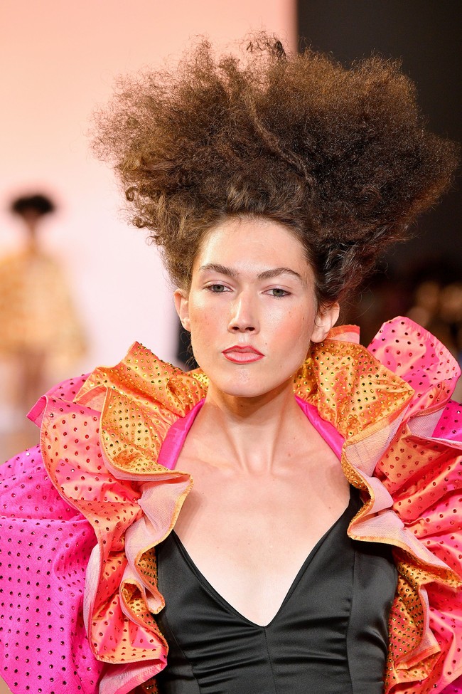 Gaya fashion yang nyentrik ini dikenakan oleh model dari Christopher John Rogers. Dalam fashion show tersebut, rambut sang model terlihat ditata ke arah atas. Untuk makeup, model terlihat seperti hanya menggunakan lip liner untuk membentuk bibir, blush on dan sedikit eyeshadow berwarna soft pink. Foto: Getty Images