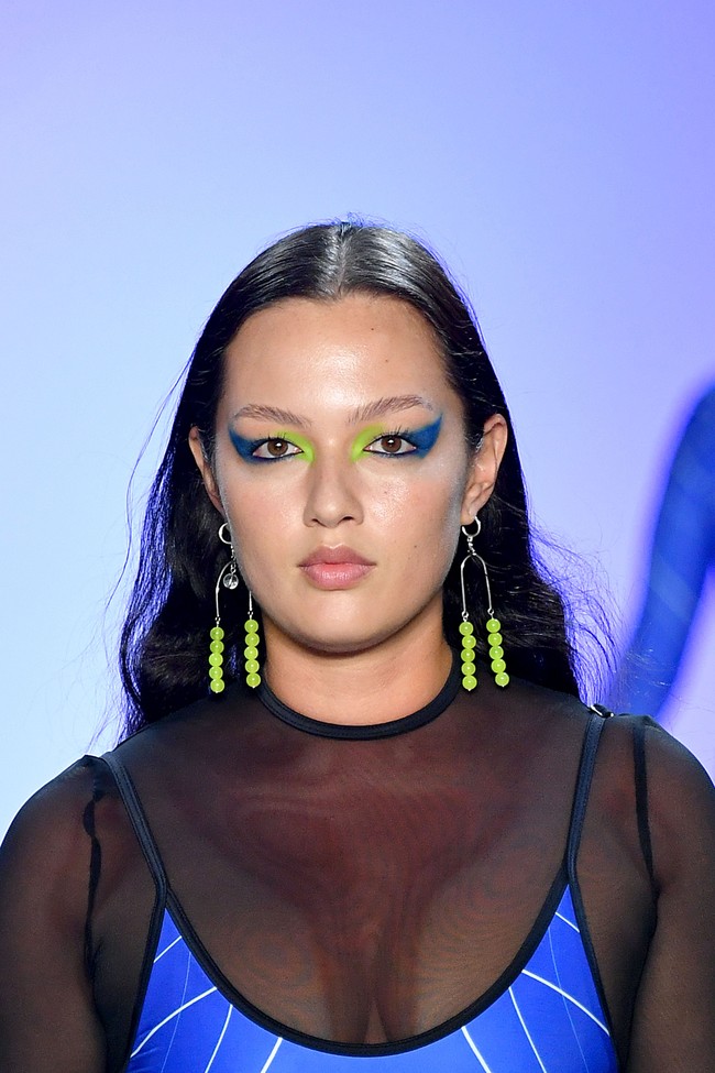 Makeup Artist Fatima Thomas yang mendandani model untuk show Chromat di New York Fashion Week 2020 membuat tampilan cukup intens. Fatima membuat riasan mata dengan menggabungkan dua warna terang, yaitu warna hijau dan biru. Ini membuat riasan jadi terfokus pada bagian mata. Foto: Getty Images