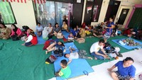 Korban kebakaran duduk dan tidur dengan beralaskan karpet di lokasi pengungsian.