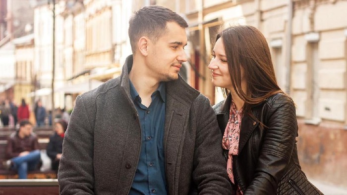 Happy couple in love outdoors looking at each other and smiling. Toned moody picture.