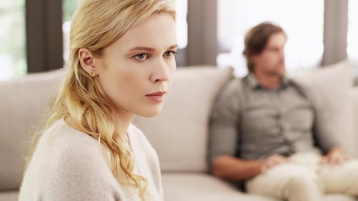 Relationship problems. Man consoling woman after argument, sitting on sofa