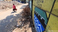 Seorang warga melintas di depan bangunan rumah yang telah rata dengan tanah.