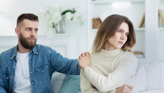 Relationship problems. Man consoling woman after argument, sitting on sofa
