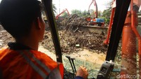 Para petugas terus bekerja membersihkan sampah yang nyangkut di pintu air Manggarai.