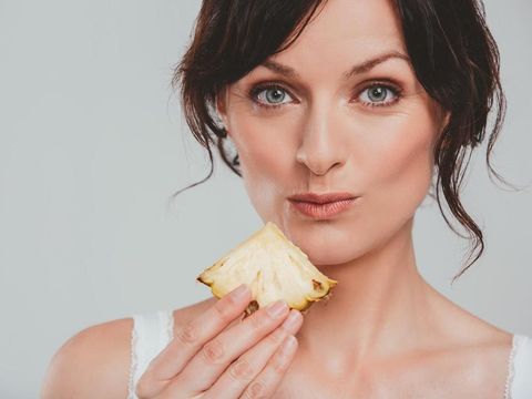 Studio shot of an attractive woman eating a snack against a gray background