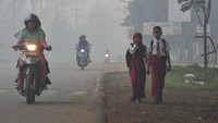 Dua orang anak sekolah nampak beraktivitas di Jalan Lintas Jambi-Muara Sabak yang diselimuti kabut asap karhutla di Muara Sabak Barat, Tanjungjabung Timur, Jambi, Rabu (9/10/2019).