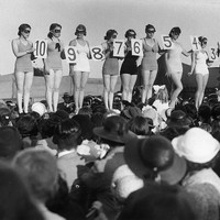 Pada zaman dahulu, peserta kontes kecantikan berparade di atas panggung dengan membawa papan nomer. Sedangkan di masa sekarang para finalis tampil dengan selempang yang menjadi identitas mereka. Biasanya pada selempang tertulis asal negara atau kota tempat tinggal mereka. Foto: Getty Images