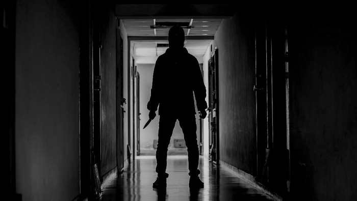 murder, kill and people concept - Criminal or murderer wearing a mask in silhouette holding knife inside a condo at crime scene