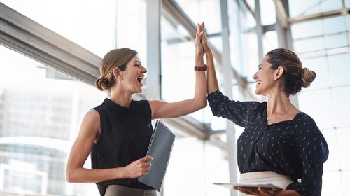 Shot of two well-dressed businesspeople high fiving in the office