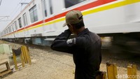 Seorang warga menjaga perlintasan kereta api tidak resmi di kawasan Beji, Depok, Jawa Barat, Jumat (11/10/2019).