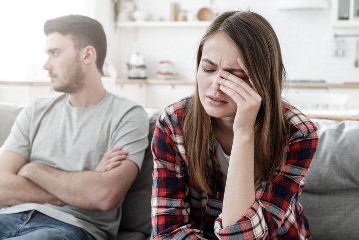zodiak Couple conflict. Stressed crying female sitting on couch with abusive husband after quarrel, ready to divorce