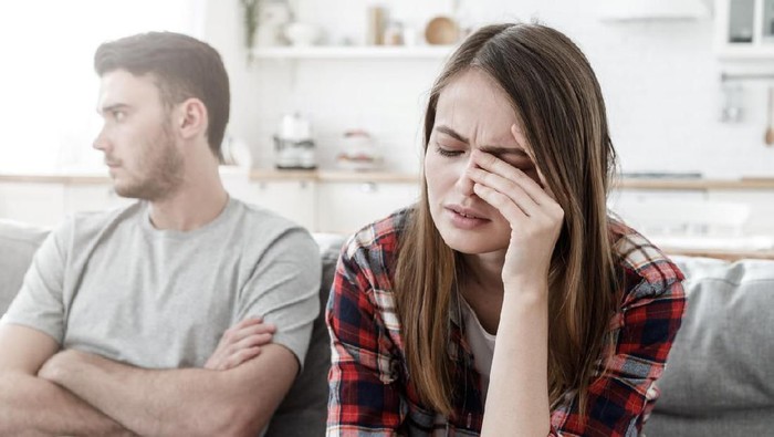 Couple conflict. Stressed crying female sitting on couch with abusive husband after quarrel, ready to divorce