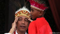 Ini momen saat Jokowi mengenakan topi rumbai khas Papua saat menerima sejumlah anak-anak dari Papua di Istana Negara, Jakarta, Jumat (11/10/2019).