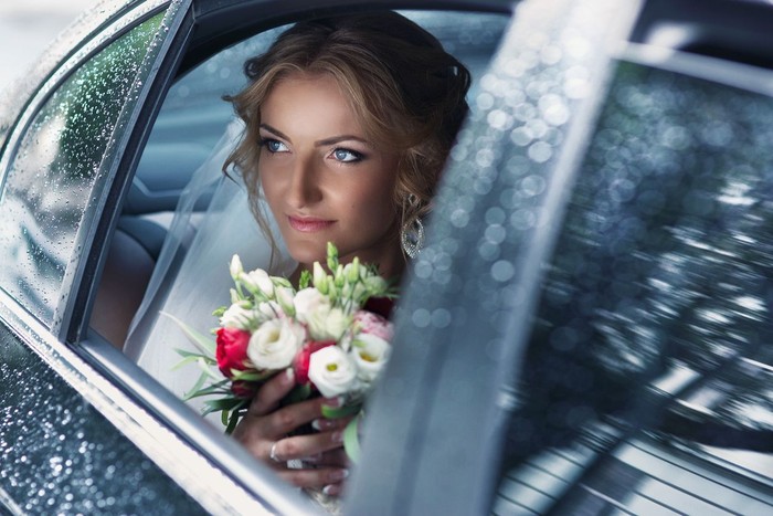 Ilustrasi pernikahan Beautiful blonde bride posing in wedding car on rainy day