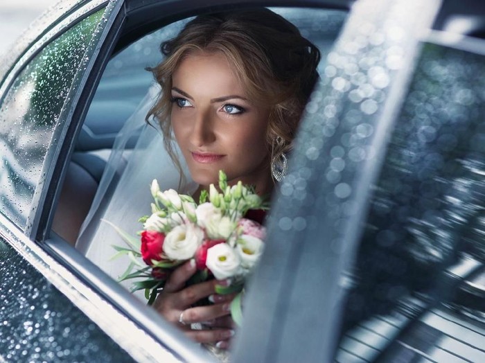 Ilustrasi pernikahan Beautiful blonde bride posing in wedding car on rainy day