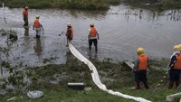 Sejumlah petugas penyelamat melakukan drainase dengan cara menyedot air menggunakan selang raksasa untuk dialirkan ke sungai untuk mengurangi luapan banjir.