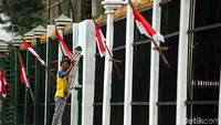 Pekerja mengecat pagar gedung DPR.