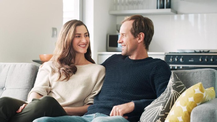 Shot of a smiling young couple talking together while relaxing in their living room
