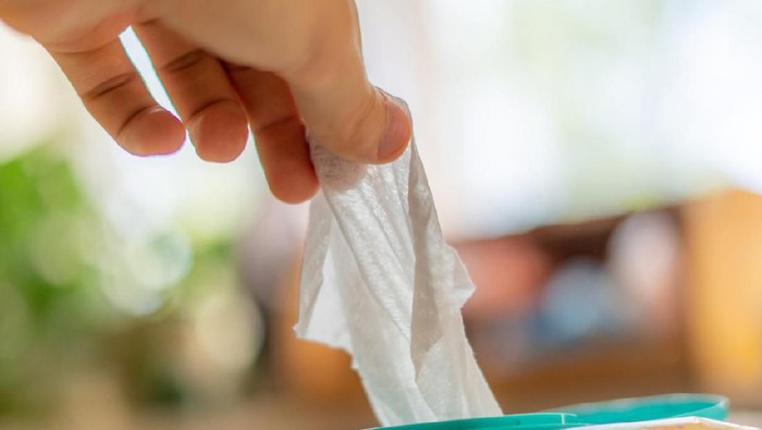 hand taking the wet wipe to clean skin