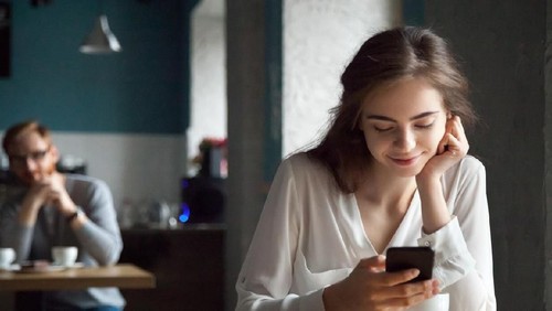 A smiling young businesswoman sits opposite an unrecognizable candidate during an interview.  She reaches across her desk to shake hands with him.