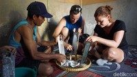 Dua orang turis mengikuti proses pembuatan minyak kelapa di Desa Kembang Kuning, Kecamatan Sikur, Kabupaten Lombok Timur. Mereka terlihat memarut kelapa.