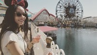 Menikmati segelas minuman sambil berpose di depan bianglala raksasa. Ternyata Zoe baru saja menghabiskan waktu liburan di Disney Land. Lihat saja bando Minnie Mouse yang menunjang penampilannya.  Foto: instagram Zoe Kravitz