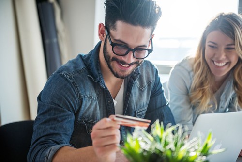 Front view of a stressed young couple facing financial problems, sitting on couch and looking at bills