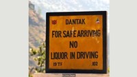 Tanda jalan ini dituliskan dalam 2 bahasa, yaitu Inggris dan Dzhongka, bahasa asli Bhutan. Bunyinya seperti ini, For Safe Driving, No Liquor in Driving. (Chris Dwyer/BBC)