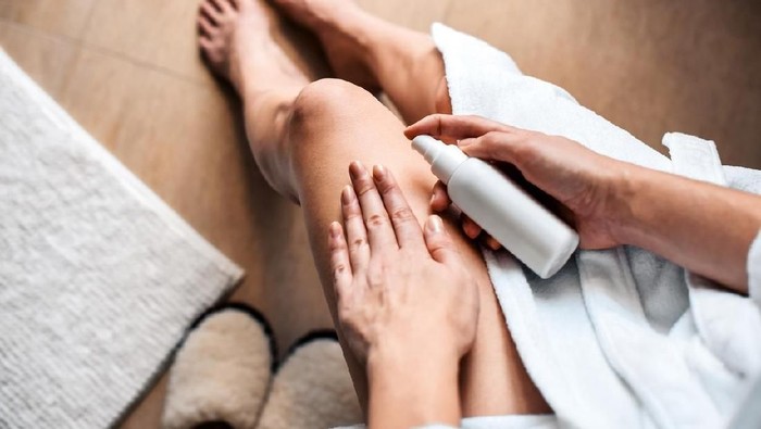 1094983248 The girl in the bathroom puts anti-cellulite cream, serum on the legs and body. Body care concept.