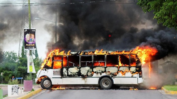 A burning bus, set alight by cartel gunmen to block a road, is pictured during clashes with federal forces following the detention of Ovidio Guzman, son of drug kingpin Joaquin 