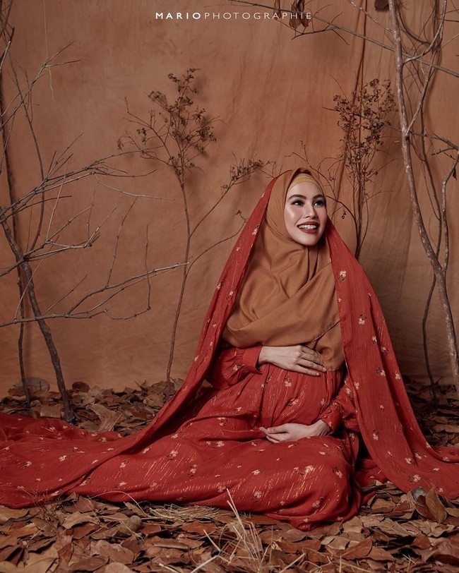 Masih dalam balutan busana Barli Asmara, Kartika Putri berpose didampingi sang suami dengan latar dedaunan kering dan ranting. Foto: instagram @mariophotographie