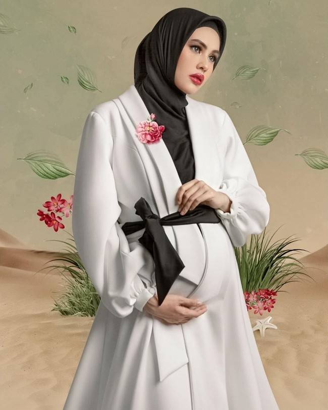Kartika Putri bergaya monokrom dengan tampilan hitam putih di pemotretan kehamilannya. Kartika mengenakan hijab hitam dan dres putih rancangan dari Tommy Panca Murti. Kartika Putri kali ini tampak berbeda karena tidak mengenakan hijab syar’i seperti gayanya sehari-hari. Foto: instagram @kartikaputriworld