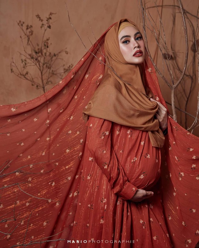 Sebelum melahirkan Kartika Putri melakukan foto kehamilan dengan berbagai gaya hijab. Seperti pada foto ini, Kartika tampak cantik dalam balutan busana dari Barli Asmana. Dia menerapkan gaya hijab syari berwarna cokelat yang dipadukan dengan selendang panjang berwarna senada dengan gaunnya. Foto: instagram @mariophotographie.