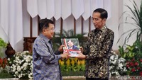 Dalam kesempatan ini, JK juga memberikan buku yang sampulnya terdapat foto JK kepada Jokowi di atas podium.