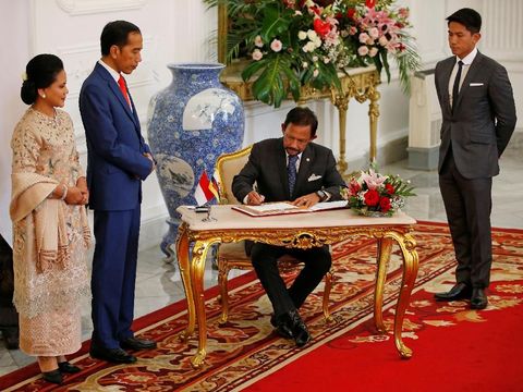 BruneiÕs Sultan Hassanal Bolkiah sign a guest book as Indonesian President Joko Widodo and Indonesian First Lady Iriana Widodo stand at the Presidential Palace in Jakarta, Indonesia, October 20, 2019. REUTERS/Willy Kurniawan