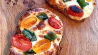  Irisan tomat ceri dan daun basil bisa jadi paduan yang pas buat roti panggang dengan taburan keju mozzarella. Nikmati gurih mulurnya. Foto Instagram @flona_dawson
