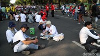 Ada banyak relawan Jokowi-Maruf Amin di tempat ini. Terlihat, para relawan ini sedang memesan makanan. Seorang polisi menjelaskan penyediaan sajian kaki lima secara gratis ini diinisiasi oleh Ketua Panitia Syukuran Inaugurasi Presiden dan Wakil Presiden.