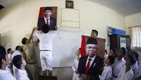 Siswa SD Negeri Joglo Solo dibantu guru memasang foto Presiden Joko Widodo dan Wakil Presiden Maruf Amin di ruang kelas sekolahnya di Solo, Jawa Tengah, Senin (21/10/2019). Antara Foto/Maulana Surya