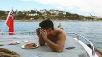 Bersantai di atas kapal, Pangeran Mateen habiskan waktu luang dengan mengabadikan pemandangan di sana, ditemani dengan irisan buah semangka yang segar. Foto: Instagram @tmski