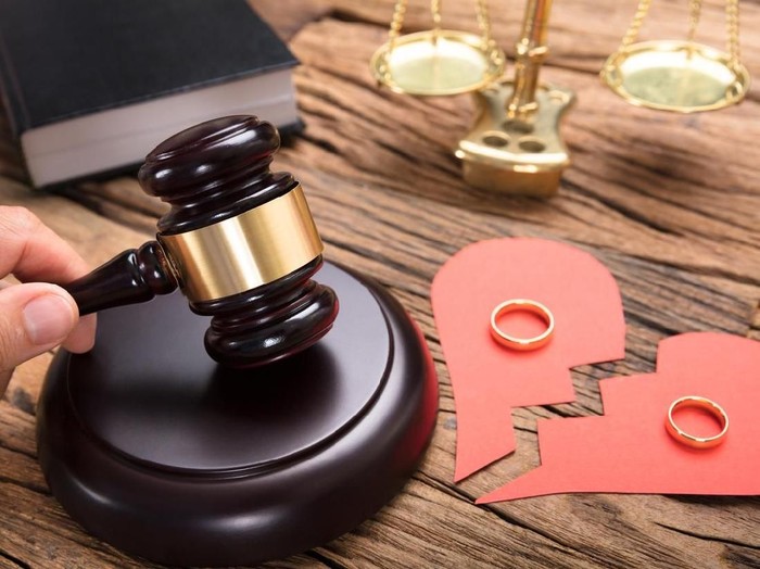 Judge hitting mallet by broken paper heart with rings and justice scale on wooden table