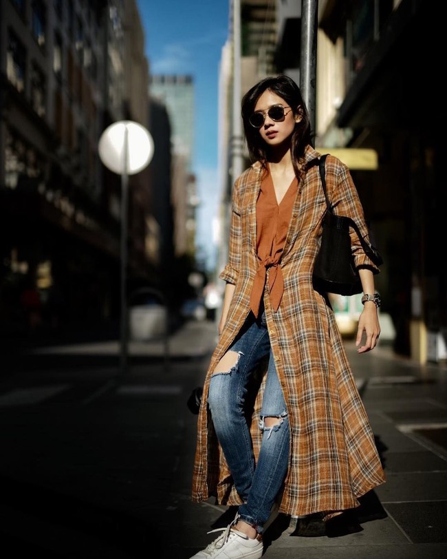 Gista mengubah fungsi kemeja panjang kotak-kotaknya menjadi outerwear. Dia memadankannya dengan blouse coklat dan celana jeans. Padu padannya ini tampak effortless.  Foto: dok. Instagram @gistaputri