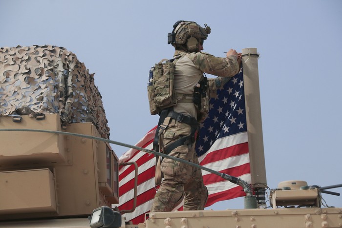 American soldier mount the U.S. flag on a vehicle near the town of Tel Tamr, north Syria, Sunday, Oct. 20, 2019. Kurdish-led fighters and Turkish-backed forces clashed sporadically Sunday in northeastern Syria amid efforts to work out a Kurdish evacuation from a besieged border town, the first pull-back under the terms of a U.S.-brokered cease-fire. (AP Photo/Baderkhan Ahmad)