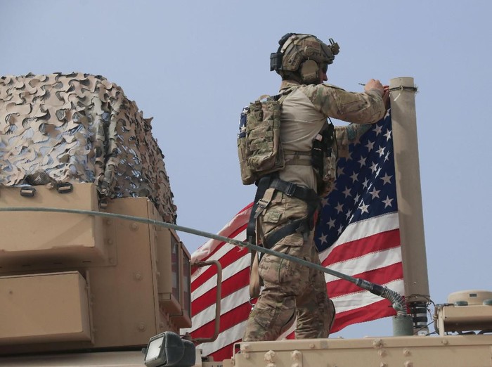 American soldier mount the U.S. flag on a vehicle near the town of Tel Tamr, north Syria, Sunday, Oct. 20, 2019. Kurdish-led fighters and Turkish-backed forces clashed sporadically Sunday in northeastern Syria amid efforts to work out a Kurdish evacuation from a besieged border town, the first pull-back under the terms of a U.S.-brokered cease-fire. (AP Photo/Baderkhan Ahmad)