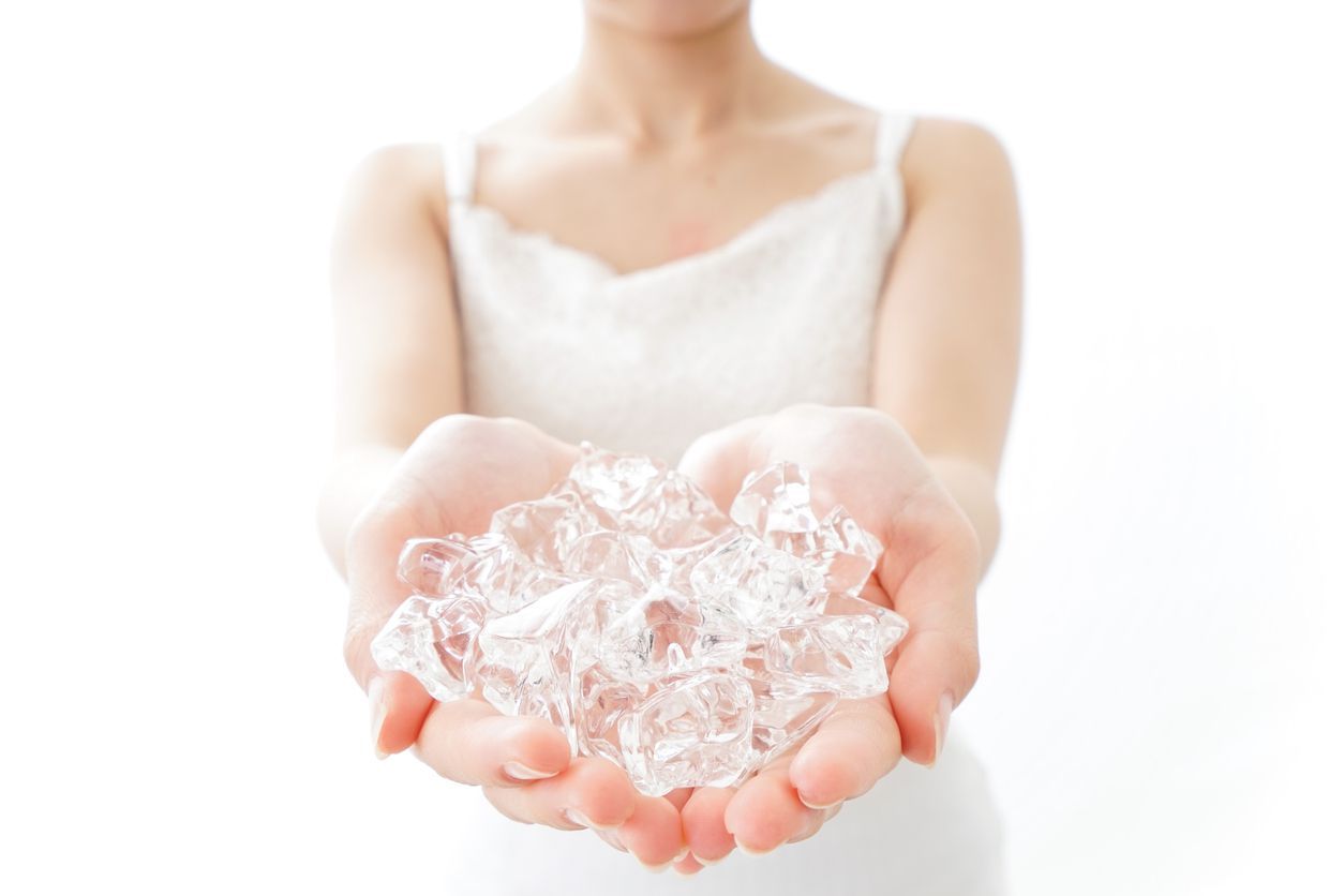 brunette woman holding ice cube on her face